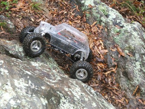1996 Ford Bronco - This remote control rock crawler navigates a challenging, wet, and rocky terrain covered in fallen leaves.