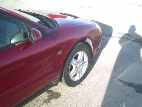 2000 Ford Taurus - A red sedan is viewed from the front quarter, showing its side panel and wheel.