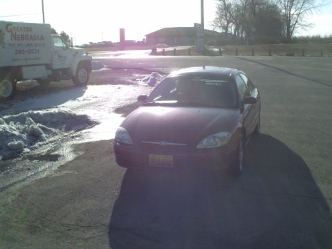 2000 Ford Taurus - A dark sedan is parked next to a truck on a sunny day.