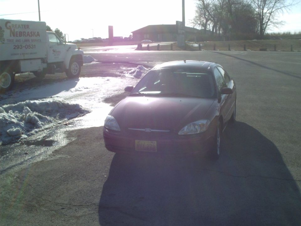 Dark sedan front view. A truck is visible to the left
