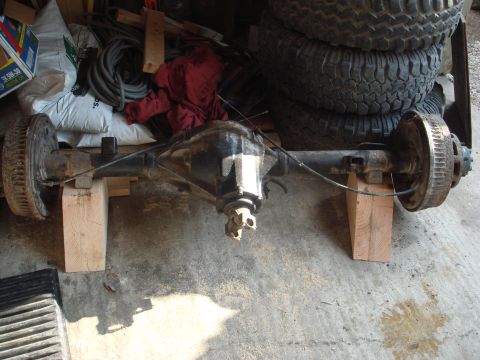 1978 Chevrolet C/K Pickup - Rear axle assembly supported by wooden blocks, with tires and other items in the background.