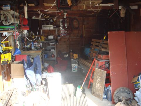 1978 Chevrolet C/K Pickup - A disorganized garage is filled with various tools, equipment, and stored materials.