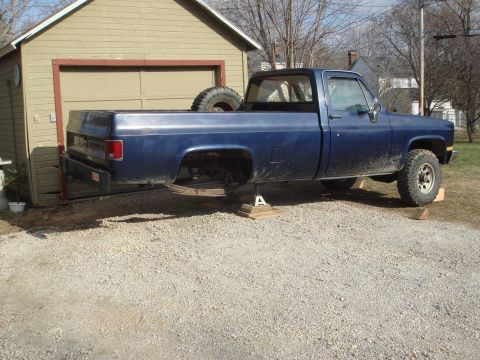 1978 Chevrolet C/K Pickup - This blue 1978 Chevrolet C/K Pickup truck is elevated on jack stands, suggesting it is undergoing maintenance or modification.