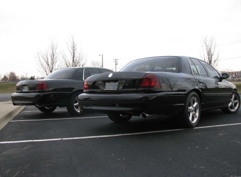 2003 Mercury Marauder - Two black sedans are parked side-by-side in a parking lot on an overcast day.