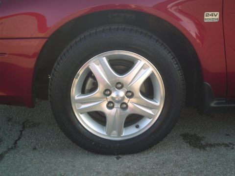 2000 Ford Taurus - A close-up shot focuses on the wheel and side panel of a red vehicle, revealing a '24V DOHC' emblem.