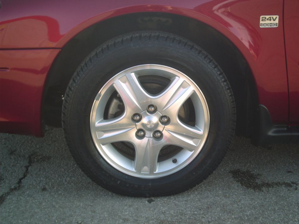 close-up of a red car's front wheel and fender, with a '24V DOHC' badge visible