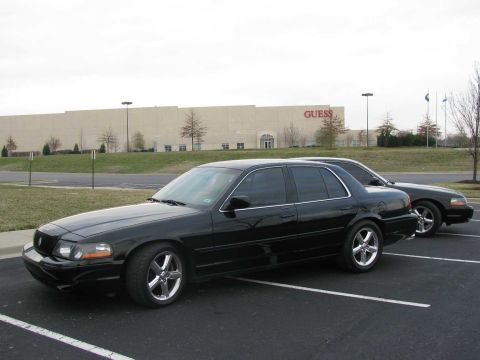2003 Mercury Marauder - Two black sedans, one a 2003 Mercury Marauder, are parked in a lot with a GUESS building in the background.