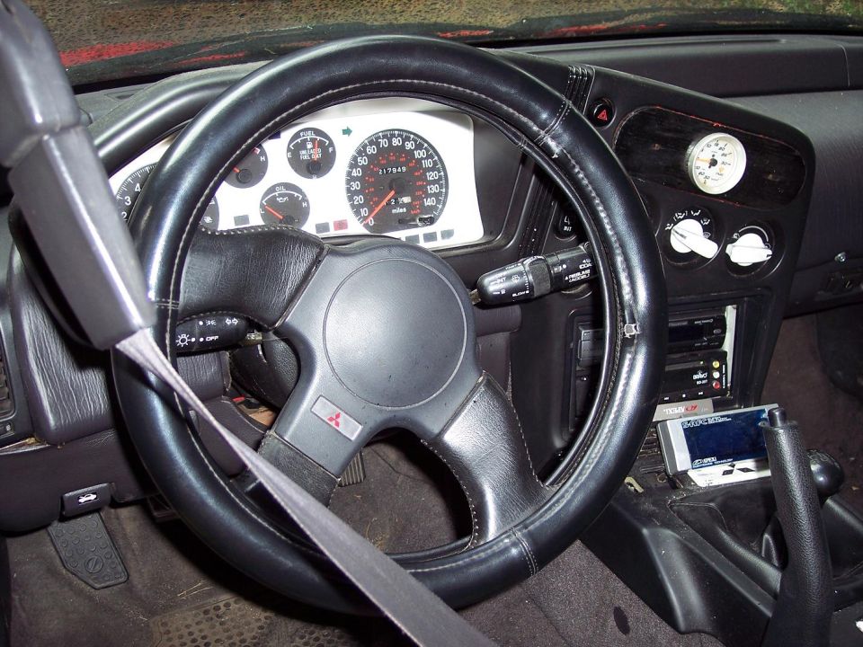 Interior shot of a 1992 Mitsubishi Eclipse, showing the steering wheel, dashboard, and gauges
