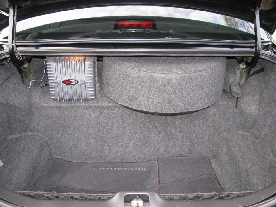 Sedan trunk interior with mounted amplifier and gray carpeted subwoofer enclosure