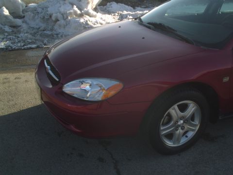 2000 Ford Taurus - A red 2000 Ford Taurus is viewed from the front quarter angle, with snow visible in the background.