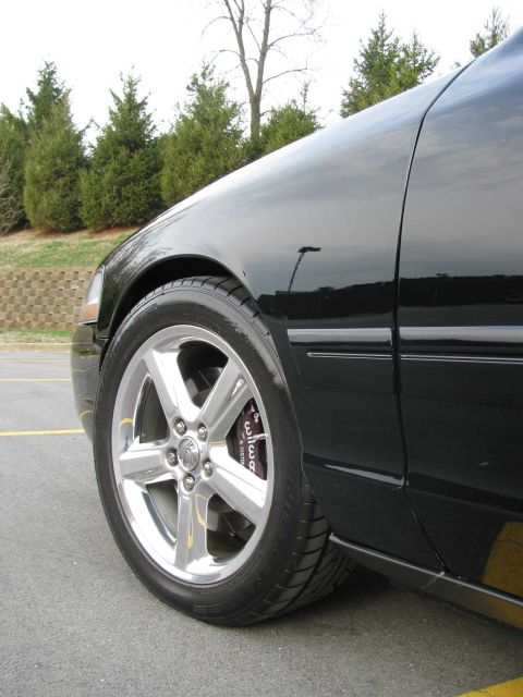 2003 Mercury Marauder - Close-up of the front wheel and fender of a black 2003 Mercury Marauder, highlighting its chrome rims and brake calipers.