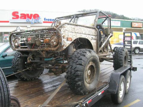 1992 Ford Mustang - This heavily modified off-road vehicle, likely a Ford Bronco, is loaded onto a trailer in front of a Save-a-Lot grocery store.