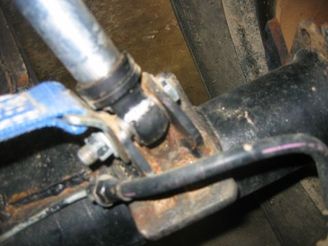1992 Ford Mustang - A close-up view of a vehicle's suspension system, showing a rusty metal component and a blue strap.