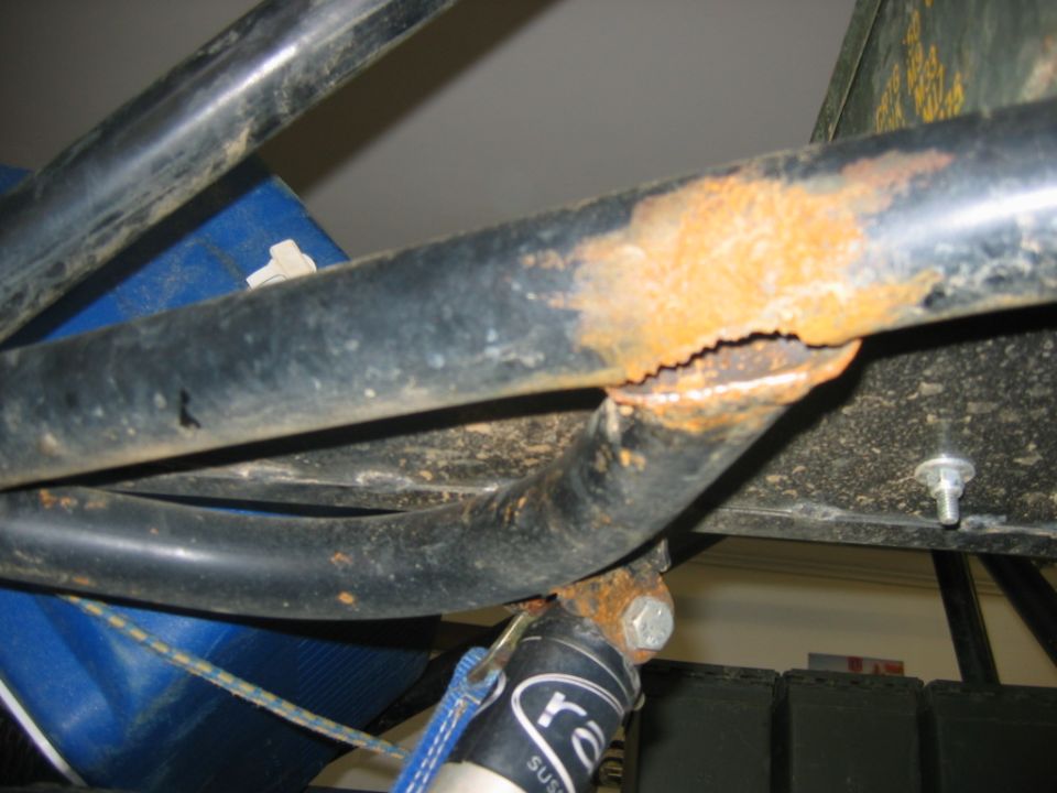 rusted and corroded black metal tubing, part of a frame or suspension system