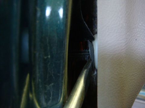 1996 Ford Bronco - A tool is used to pry open the interior door panel of a vehicle.