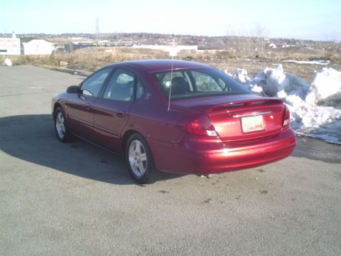 2000 Ford Taurus - Red sedan with a spoiler and a license plate is seen from the rear quarter angle.