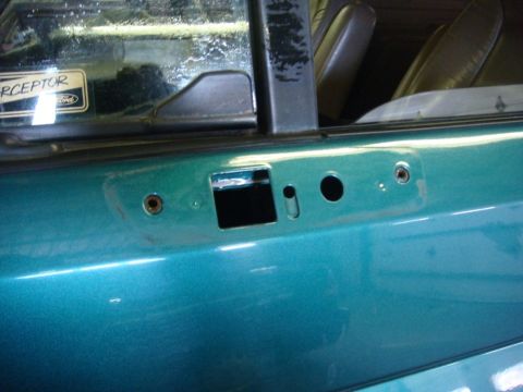1996 Ford Bronco - Close-up of a teal vehicle door panel, revealing mounting points for exterior mirrors and interior door components.