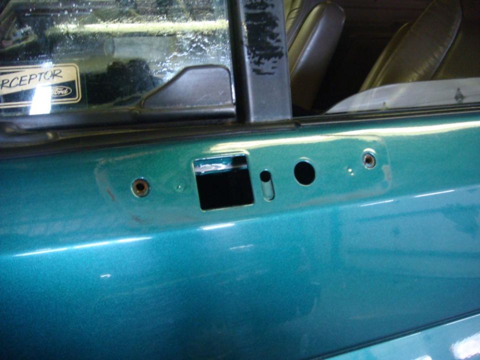 Teal door panel with window frame, showing holes for mirror and door handle. Interior seat visible