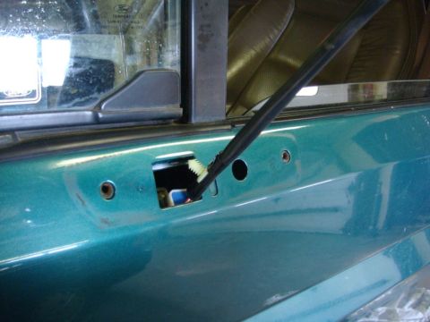 1996 Ford Bronco - Close-up of a teal door panel, revealing a wiring harness and a Ford badge on the window, suggesting a 1996 Ford Bronco.