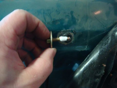1996 Ford Bronco - A hand holds a bolt and washer near a hole in a teal surface, with a black object visible to the right.
