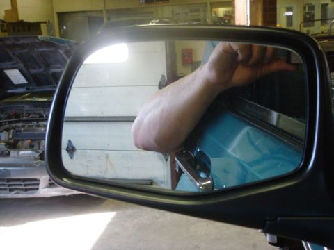 1996 Ford Bronco - Arm reaching into a vehicle, seen through the side mirror. Another car is reflected in the background.