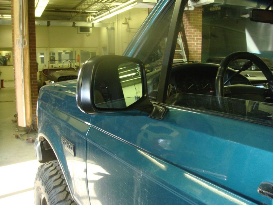 Teal 1996 Ford Bronco side view showing door panel, side mirror, and interior dashboard