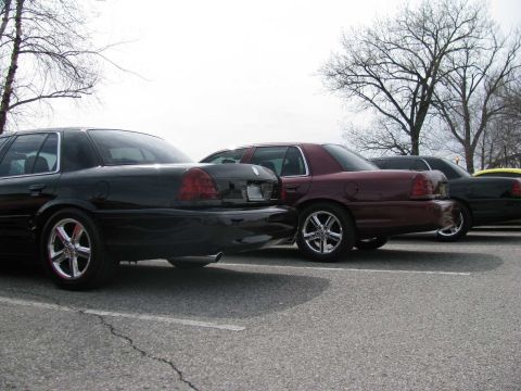 2003 Mercury Marauder - Several sedans are parked in a lot on a cloudy day, with bare trees in the background.