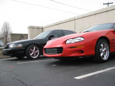 2003 Mercury Marauder - A black sedan and a red sports car are parked side-by-side in a parking lot.