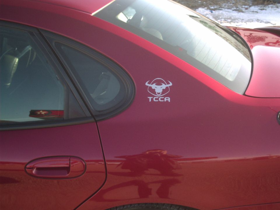 Red sedan's rear quarter panel with a TCCA bull logo on it