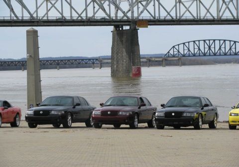 2003 Mercury Marauder - Several Mercury Marauders are parked by a river under a large bridge.