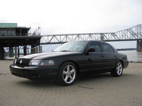 2003 Mercury Marauder - A black sedan is parked by the water with a bridge in the background.