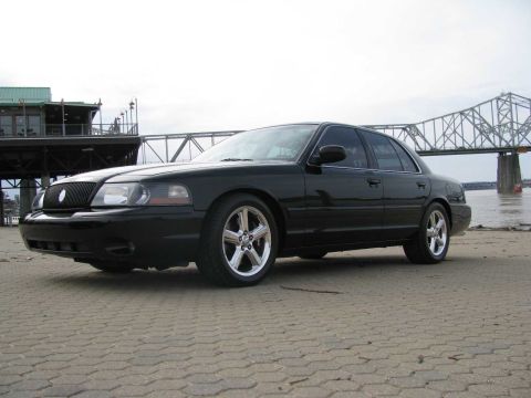 2003 Mercury Marauder - A black 2003 Mercury Marauder is parked by the water with a bridge in the background.