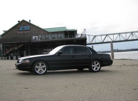 2003 Mercury Marauder - This black 2003 Mercury Marauder is parked on a paved area near a waterfront restaurant and a bridge.