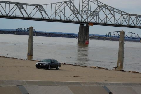 2003 Mercury Marauder - A black 2003 Mercury Marauder is parked on a sandy bank with a large bridge overhead and water in the background.