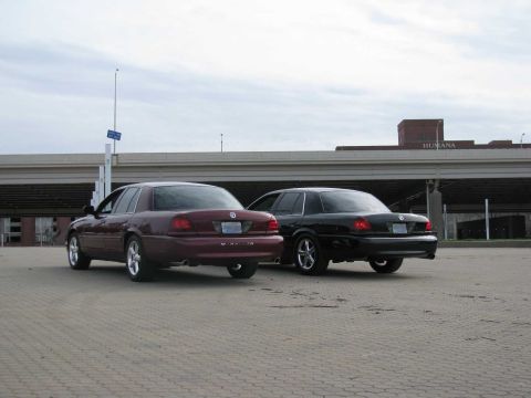 2003 Mercury Marauder - Two 2003 Mercury Marauders, one maroon and one black, are parked in a lot with an overpass in the background.