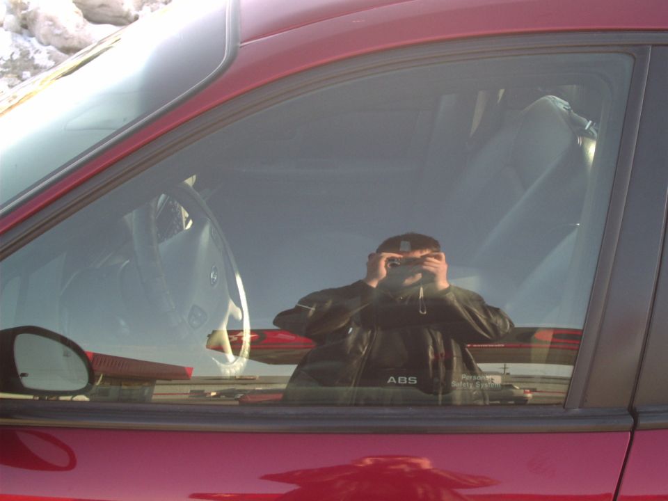 Red car interior with reflection of person taking photo. ABS text visible