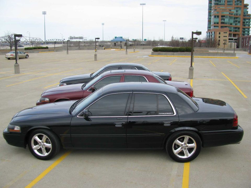 Side view of a black 2003 Mercury Marauder parked in a lot with two other cars behind it