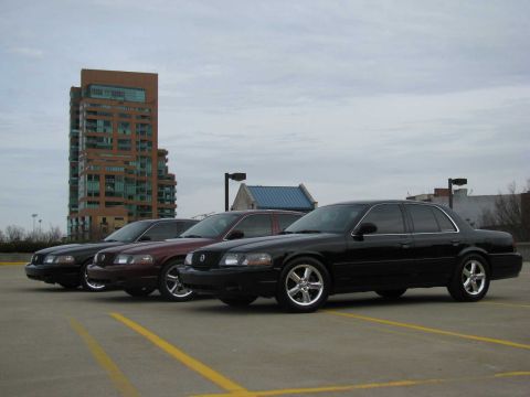 2003 Mercury Marauder - Three Mercury Marauder sedans are lined up in a parking lot under a cloudy sky.