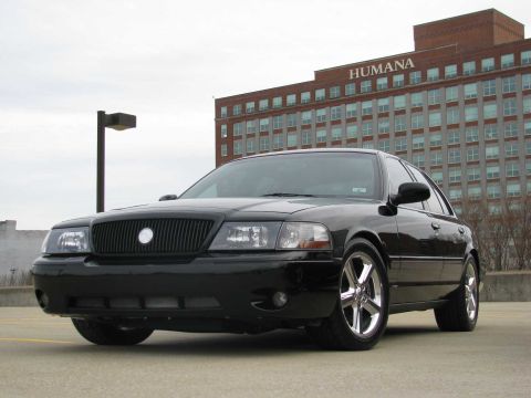 2003 Mercury Marauder - A black 2003 Mercury Marauder is parked in front of a large brick building under a cloudy sky.