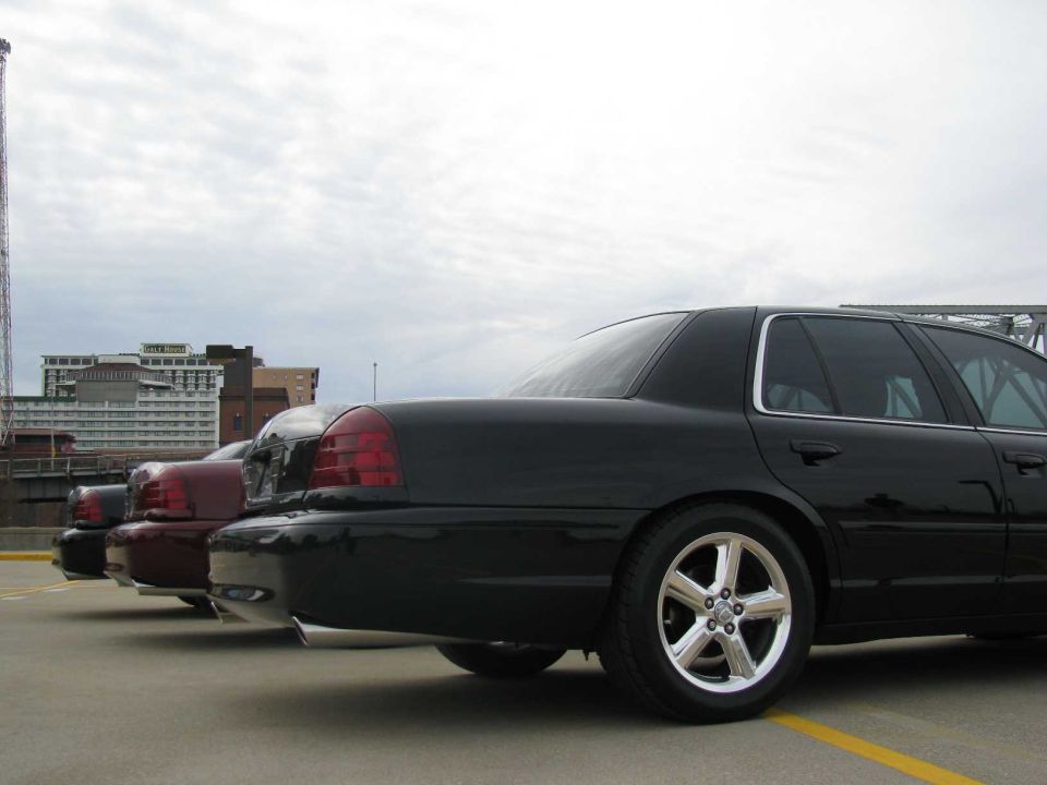 Three sedans, including a black 2003 Mercury Marauder, parked in a lot with buildings in the background