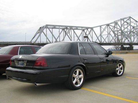 2003 Mercury Marauder - A black sedan is parked in a lot with a bridge in the background. Another vehicle is visible to the left.