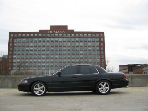 2003 Mercury Marauder - Side view of a black 2003 Mercury Marauder sedan with a large brick building in the background.