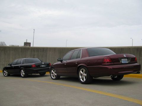 2003 Mercury Marauder - Two 2003 Mercury Marauders are seen from the rear, one maroon and one black, parked in a lot.