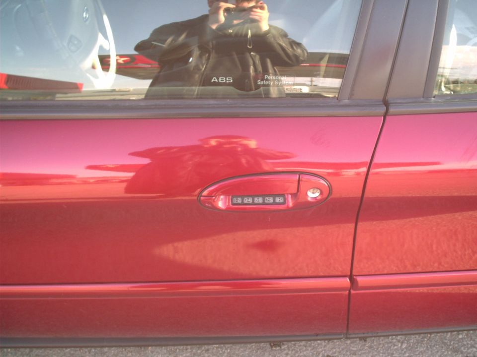 Red car door with keypad entry on the handle, side view. The car appears to be a 2000 Ford Taurus