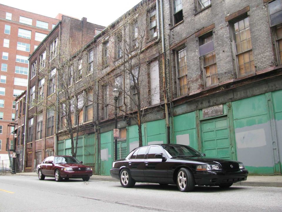 Black 2003 Mercury Marauder and a maroon sedan parked on a street in front of old brick buildings