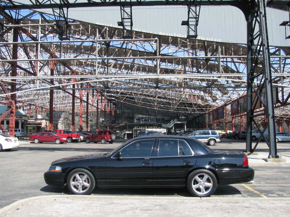 Black 2003 Mercury Marauder sedan parked outdoors, side view, with a large industrial structure in the background