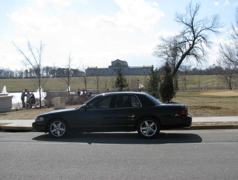 2003 Mercury Marauder - A black 2003 Mercury Marauder is parked on the side of the road with a building and trees in the background.
