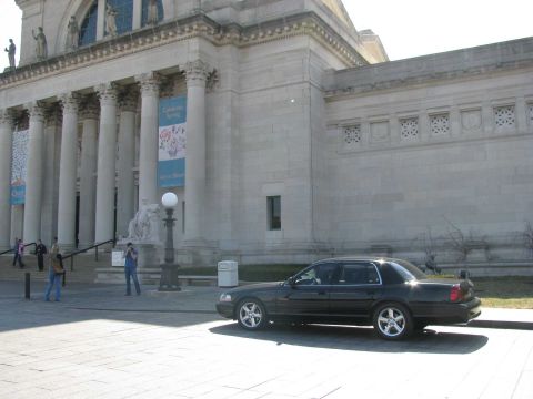 2003 Mercury Marauder - A dark sedan is parked in front of a grand building with classical architecture.