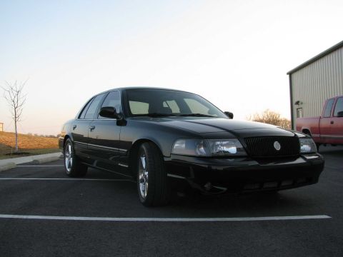2003 Mercury Marauder - A black 2003 Mercury Marauder is parked in a lot next to a building, with a red pickup truck visible.