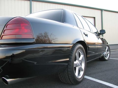 2003 Mercury Marauder - The rear of a black sedan is shown, reflecting trees and the sky.